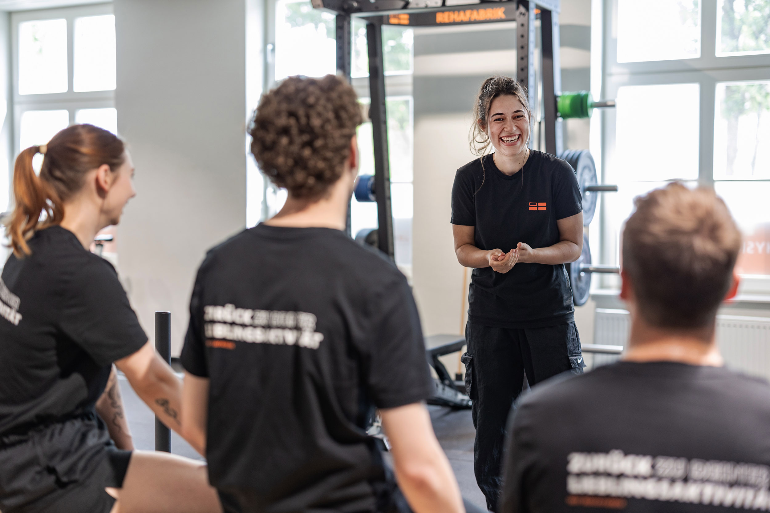 REHAFABRIK employee stands cheerfully in front of other employees