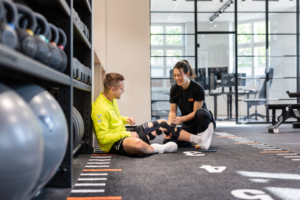 Physiotherapeutin legt Schiene beim Patienten an