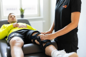 A patient wearing a knee brace is receiving physical therapy and is being treated at REHAFABRIK