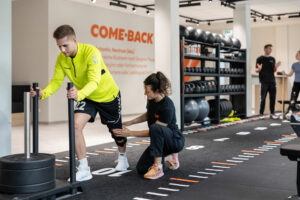 A REHAFABRIK employee assists a rehabilitation patient with a knee exercise